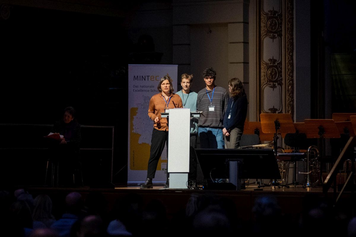 Dr. Joanna Ziomkowska on stage with Til, Nuri, and Helene during the MINT-EC School Award ceremony. © MINT-EC, Schulleitungstagung 2025 >> #SLT25